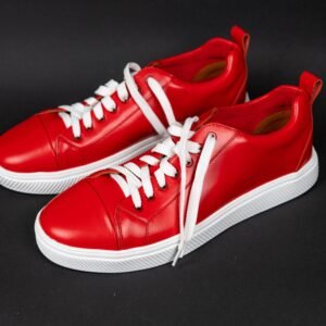 Bright red stylish sneakers with white laces on a dark background.