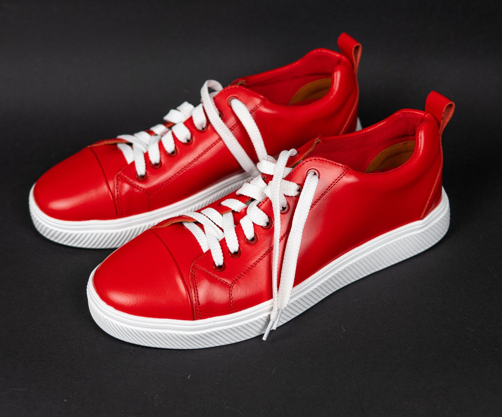 pexels photo 31688978 31688978 Bright red stylish sneakers with white laces on a dark background.