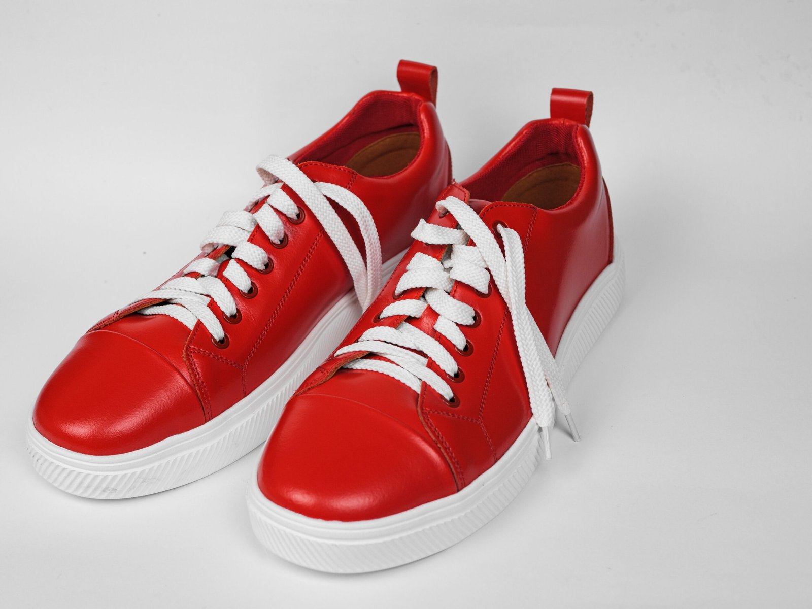 pexels photo 31688982 31688982 Pair of stylish red sneakers with white laces on a white surface.